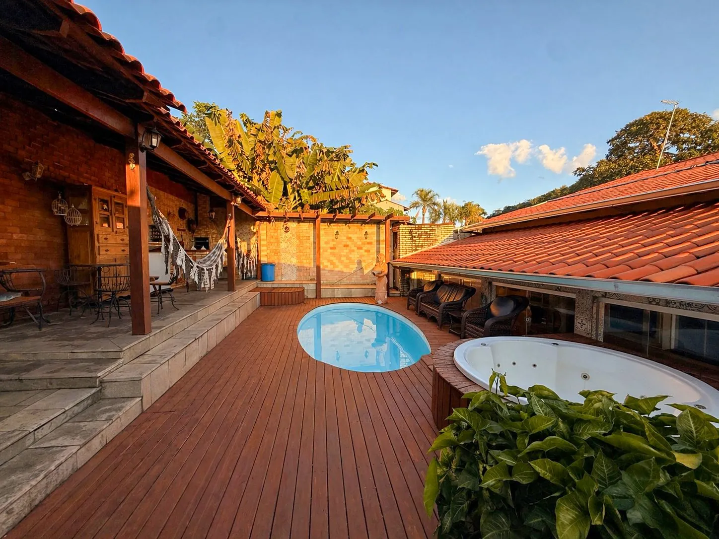 Piscina aquecida com deck de madeira ao entardecer na Casa Jardim Piri